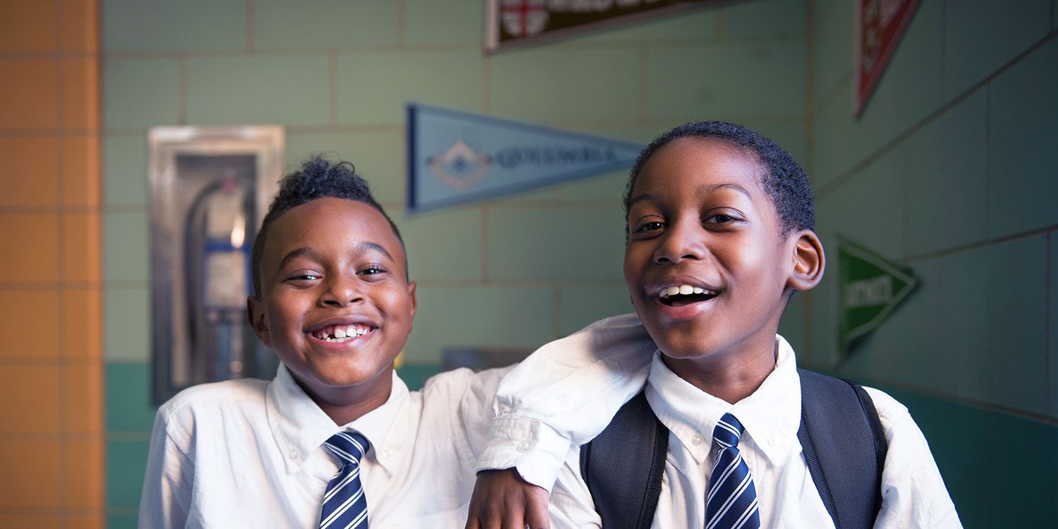 Two smiling middle-school boys in uniform